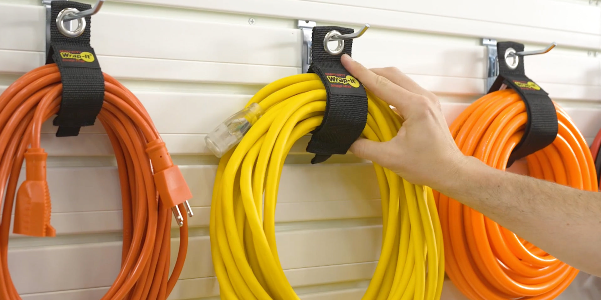Load video: video of heavy-duty wrap-it storage strap as an extension cord organizer hanging in garage, showing how to the product works for garage organization and home storage
